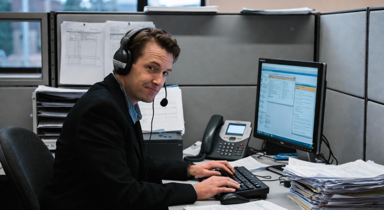 Man wearing a headset at an office computer