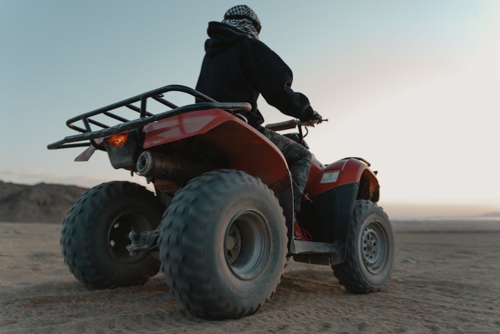 Man riding an ATV in the desert at dawn, capturing adventure and thrill.