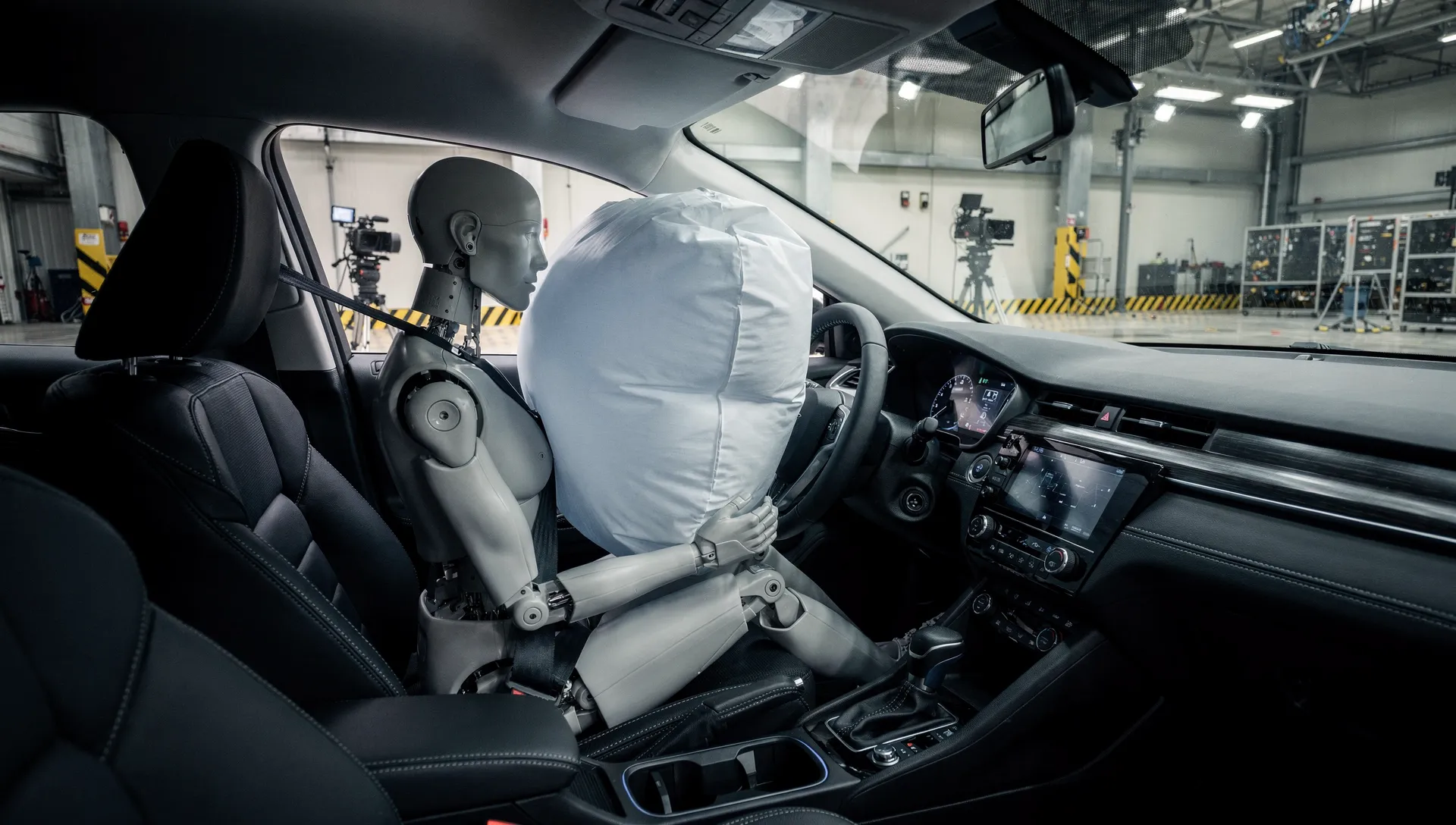Deployed driver-side airbag in a crash test, showing the full inflated bag positioned in front of the steering wheel