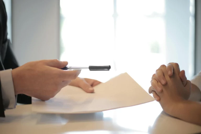 Close-up of hands signing a settlement document