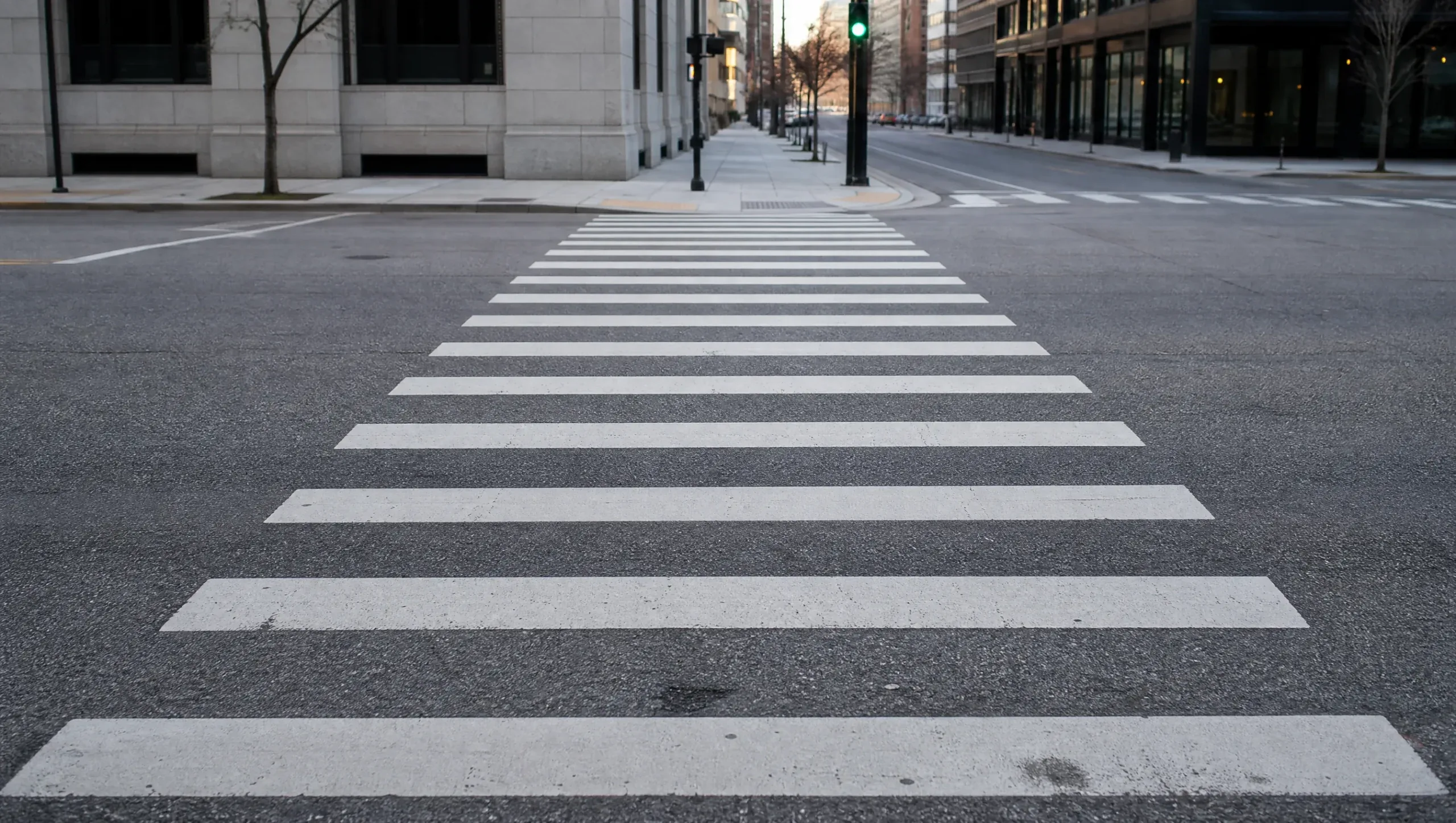 Empty marked crosswalk at a downtown intersection with a green signal