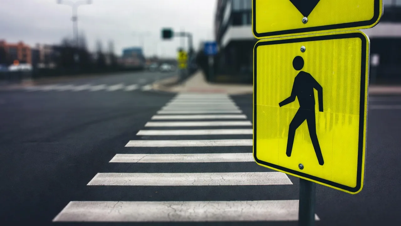 Yellow pedestrian crossing sign beside a marked crosswalk