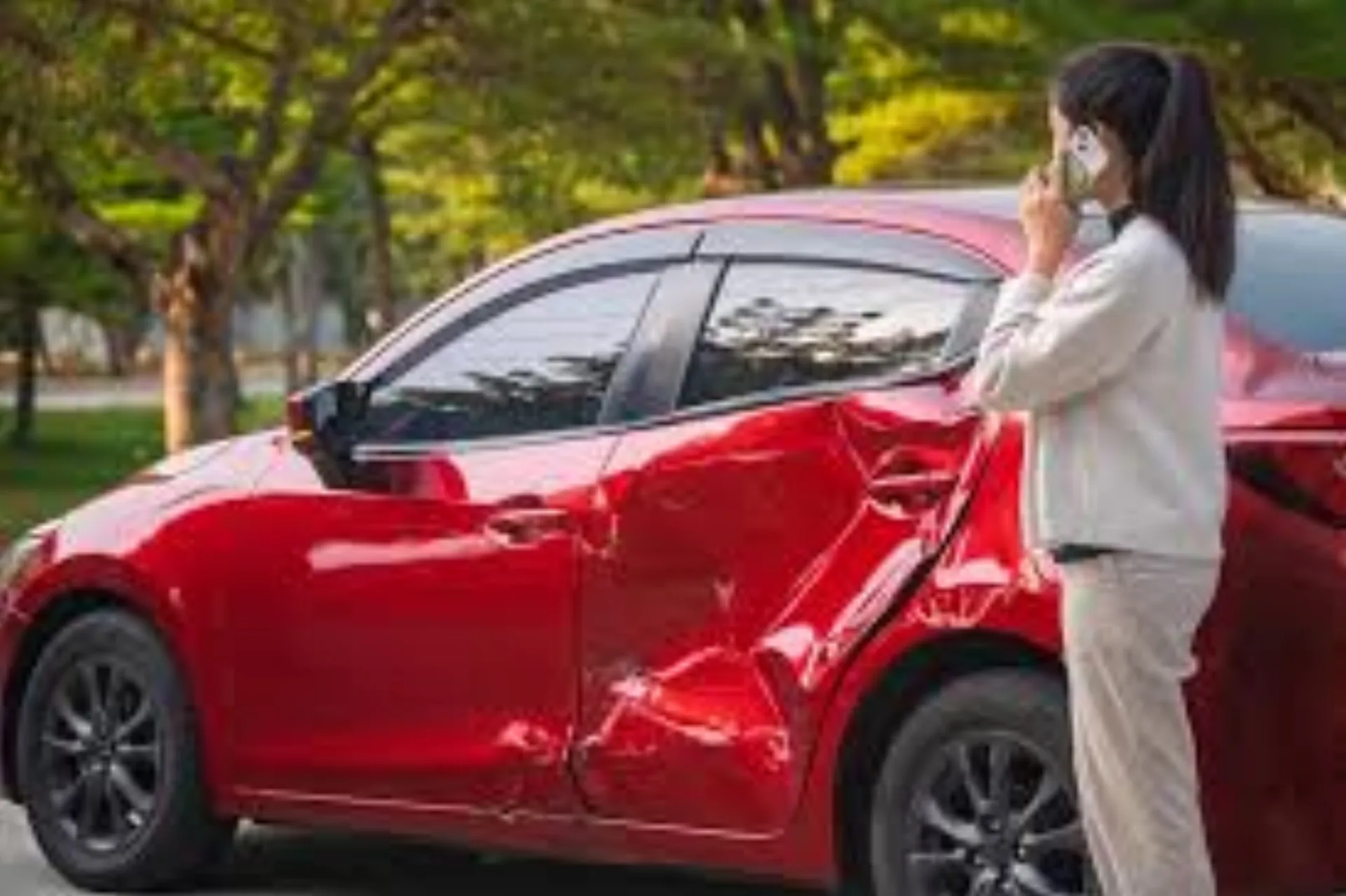 Driver calling for help beside a red car with crushed side doors