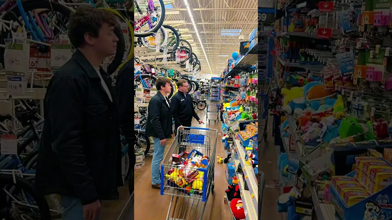 Two men pushing a shopping cart past toy and bicycle displays in a store
