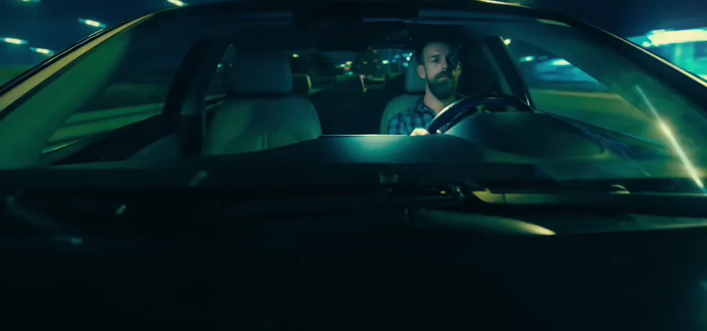 Driver behind the wheel at night as city lights sweep across the windshield