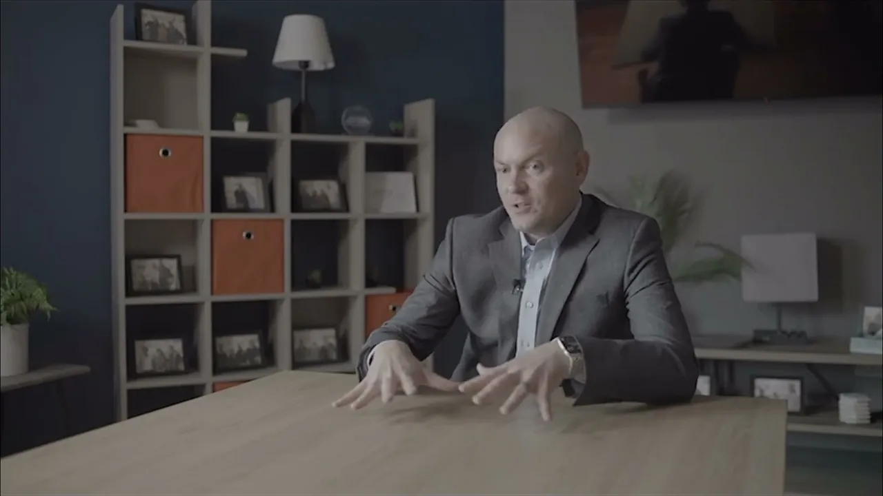 Sam Aguiar gesturing with both hands while seated at a table in the firm’s office