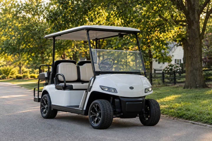 White four-seat golf cart parked on a paved neighborhood road lined with trees and a horse fence