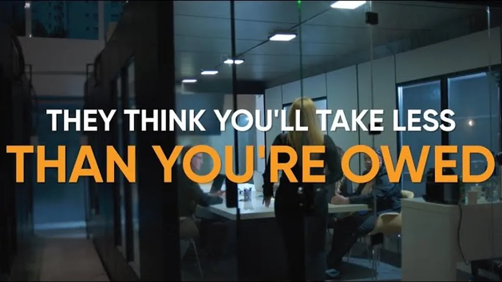 Dim glass-walled office with on-screen text reading They think you’ll take less than you’re owed