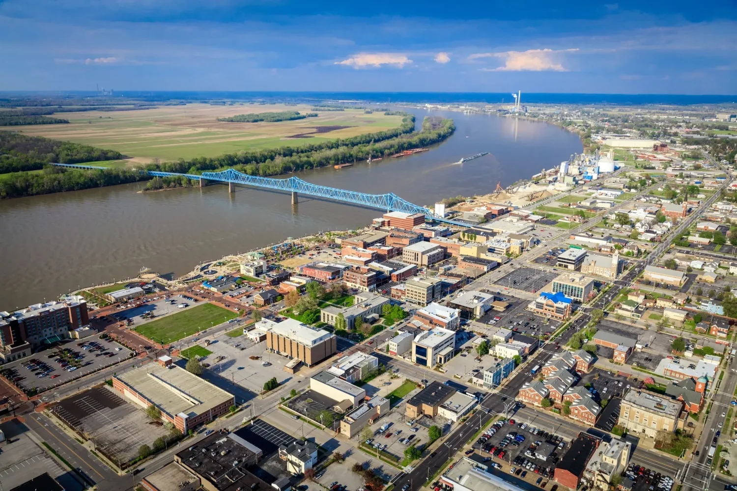 Downtown Owensboro from above, with the blue Glover Cary Bridge crossing the Ohio River and farmland on the far bank
