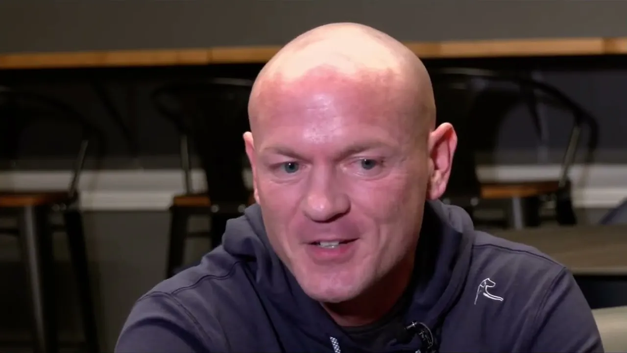 Sam Aguiar smiling in a navy pullover during an interview