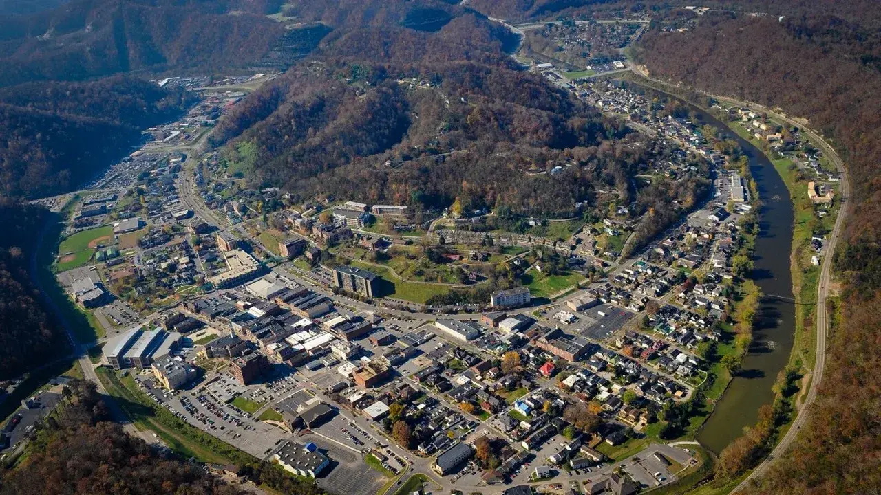 Aerial view of Pikeville in autumn, with the town along a river bend and wooded hills around it