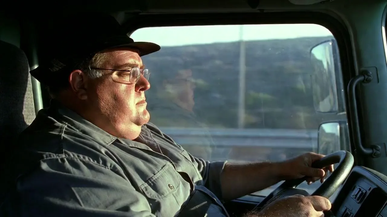 Commercial truck driver at the wheel late in a long shift, staring at the highway
