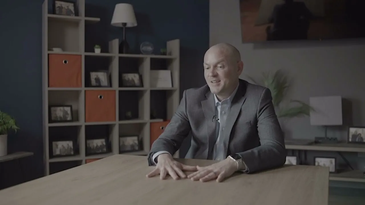 Sam Aguiar seated at a table in a firm office, speaking off camera