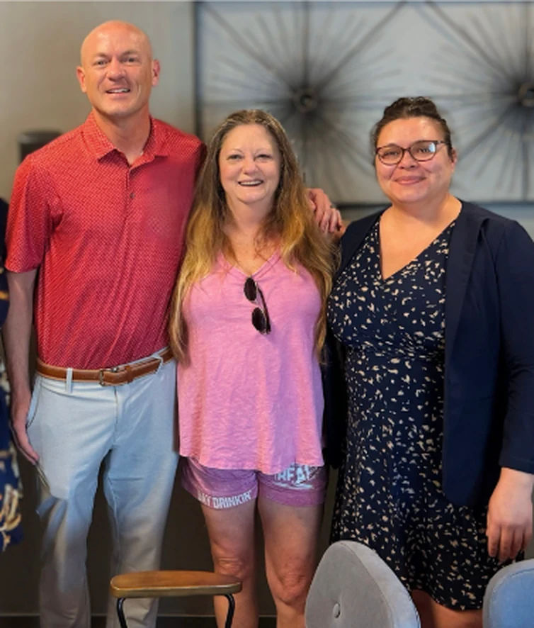 Sam Aguiar standing with two women in the firm office