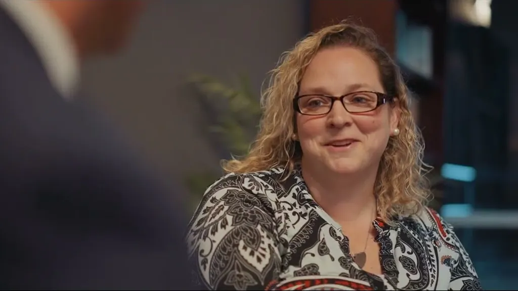 Smiling woman with glasses and curly hair in a firm interview