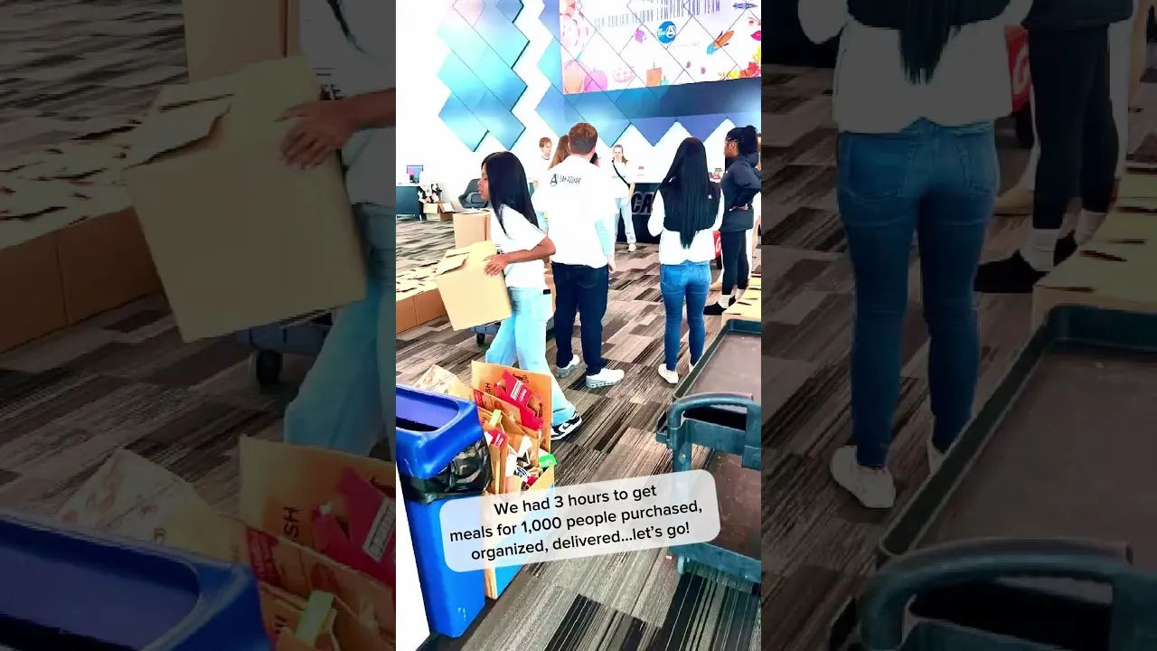 Volunteers carrying boxes in a warehouse beneath text about packing meals for 1,000 people in three hours