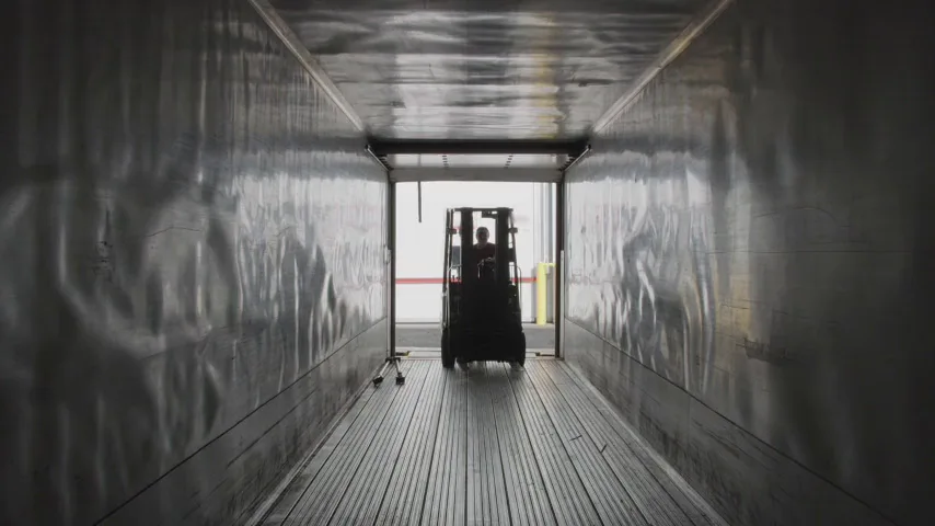 Forklift driving into an empty semi-trailer from the loading dock